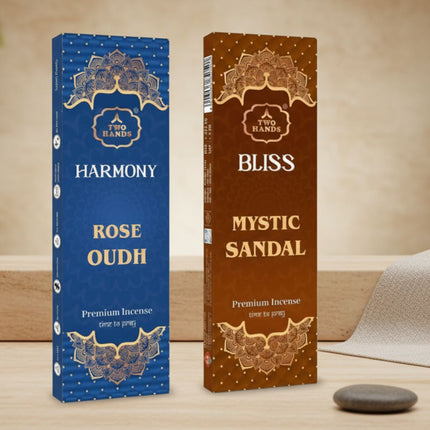 Rose Oudh and Mystic Sandal premium incense sticks boxes on a wooden surface with a zen stone.